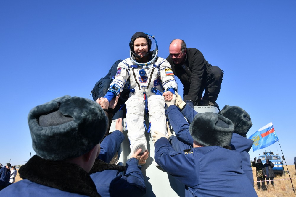 Aktris, Yulia Peresild, dibantu untuk turun setelah pendaratan kapsul ruang angkasa Soyuz MS-18 Rusia di tenggara Zhezkazgan, wilayah Karaganda, Kazakhstan (17/10). AFP/Russian Space Agency Roscosmos